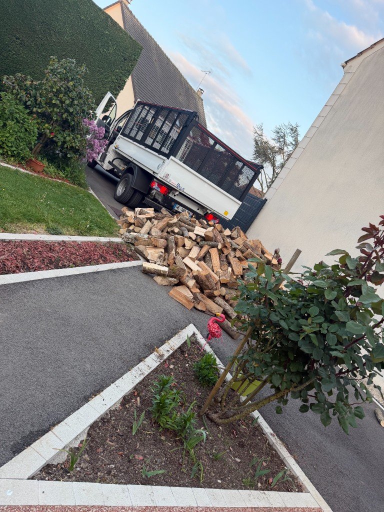 Livraison de bois de chauffage devant une maison — pile de bûches et camion ProBois77